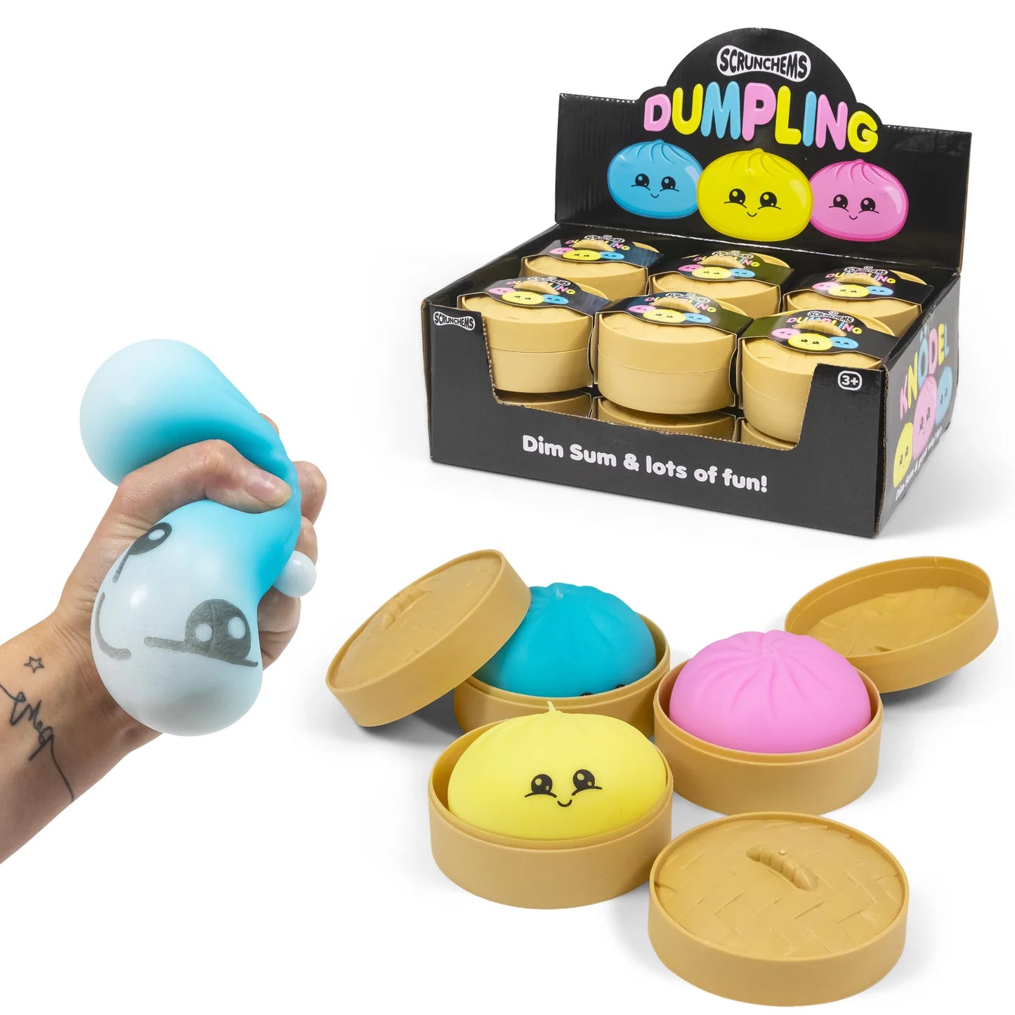 Squishy toys with smiling faces in a display box labeled 'Dumpling' by Scrunchems.