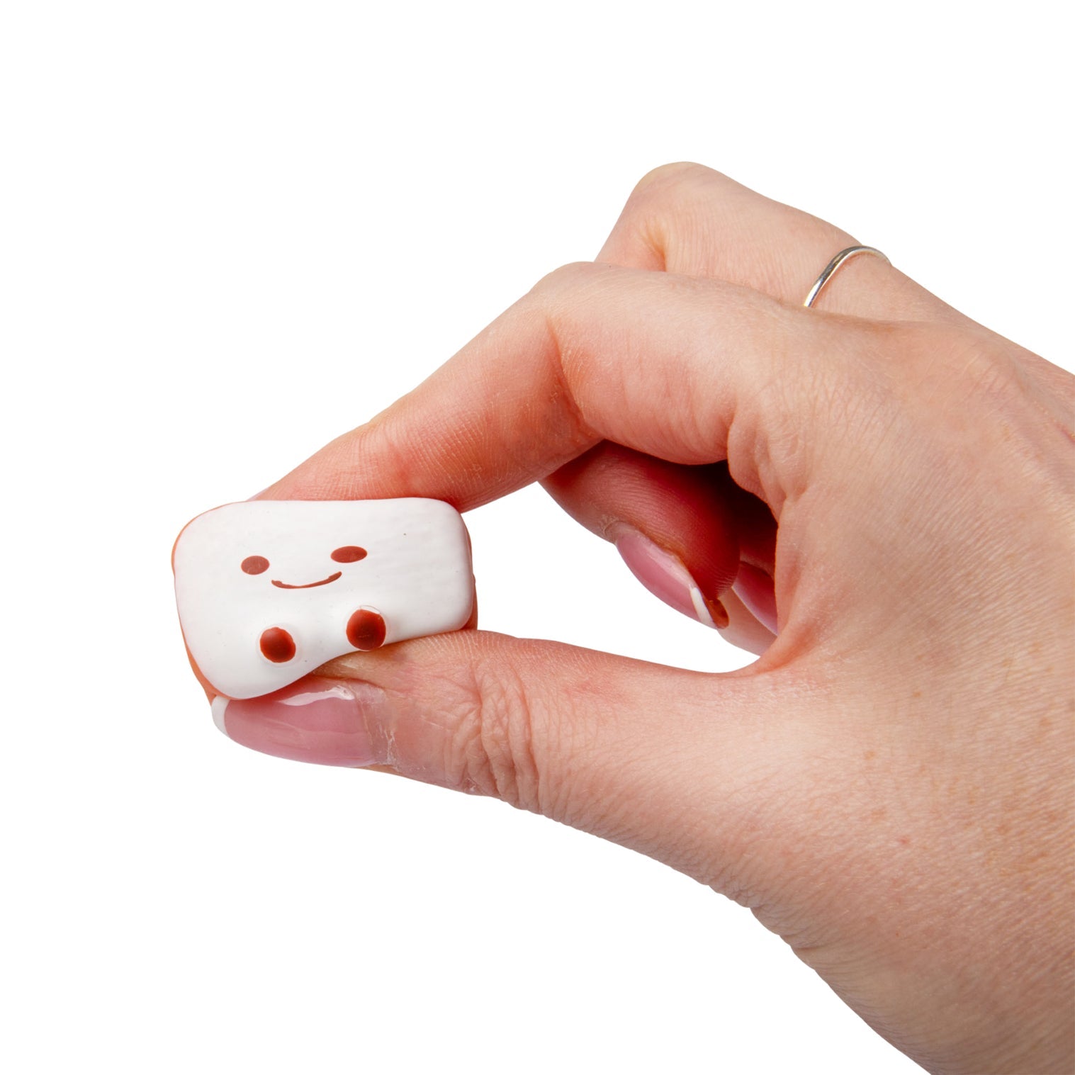 Hand holding a small white marshmallow fidget with a smiley face on a white background